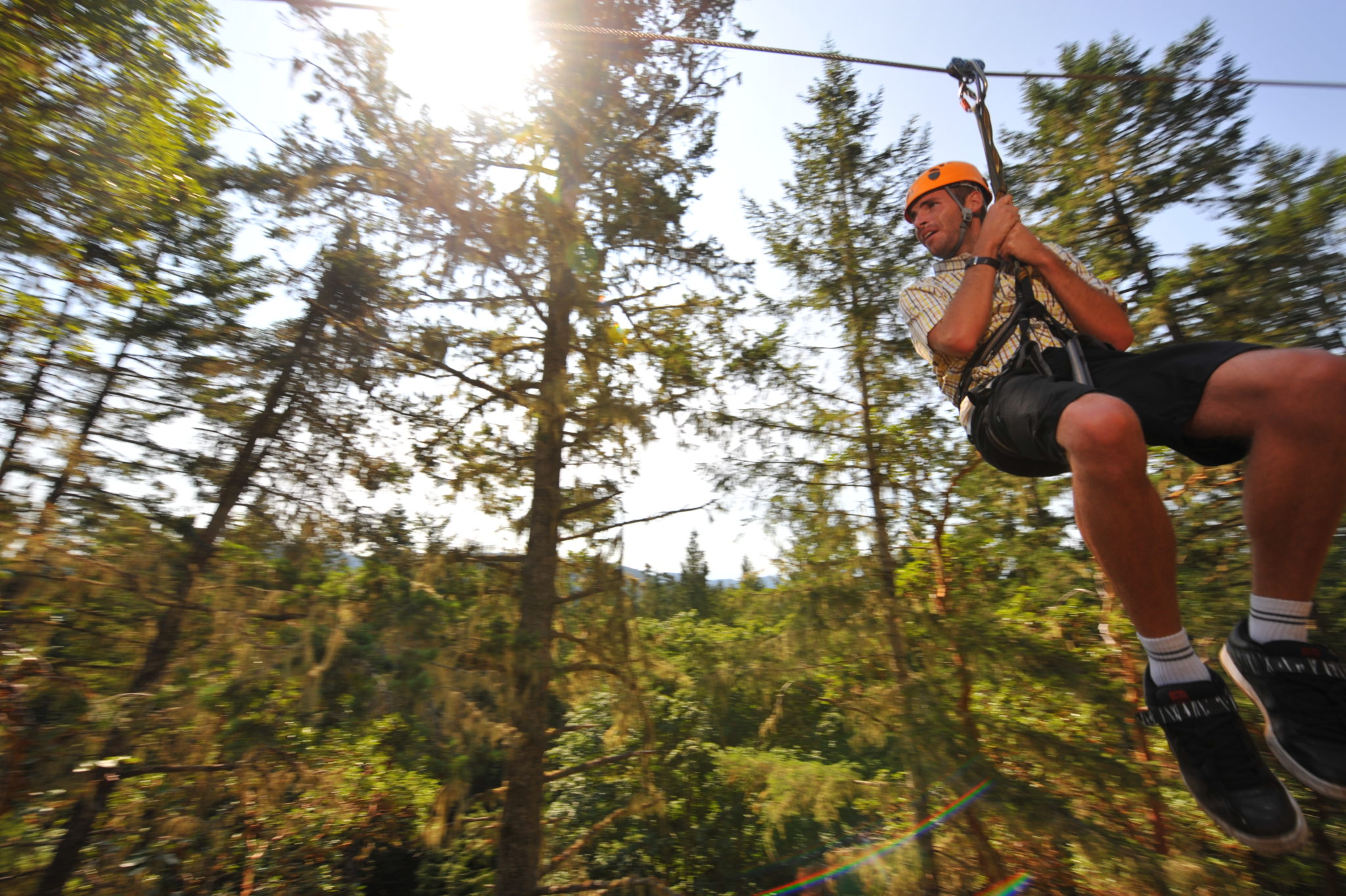 Action shot of man ziplining through trees.